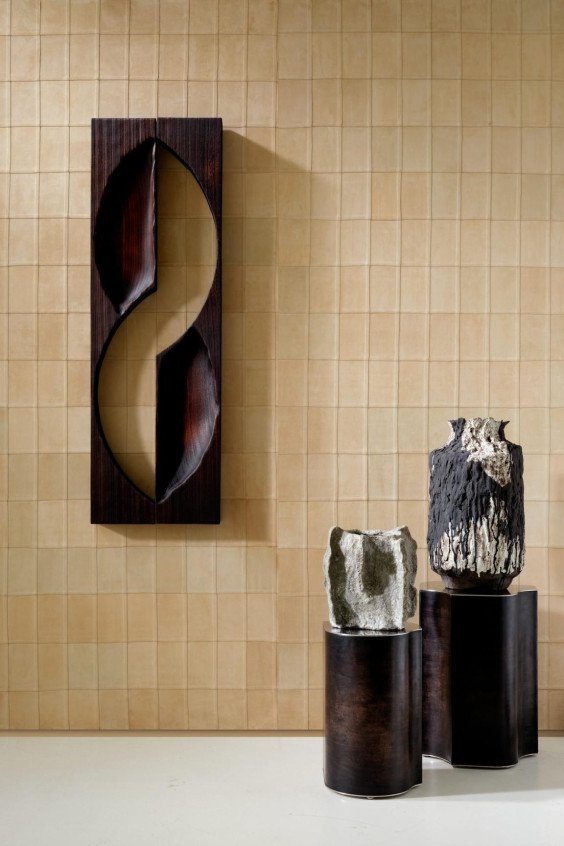 Wallshot d'une galerie d'art avec revêtement mural beige effet cuir quadrillé Corium Avenio 27470, sculpture en bois et céramiques.