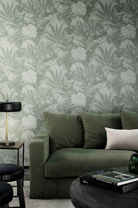 Papier peint tropical Flamant Les Mémoires Expédition vert et gris dans un salon moderne avec canapé olive.