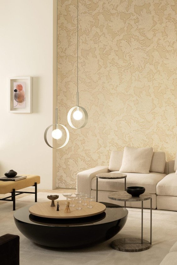 Papier peint texturé beige Zephyr Avra dans un salon moderne avec canapé clair et luminaires design.